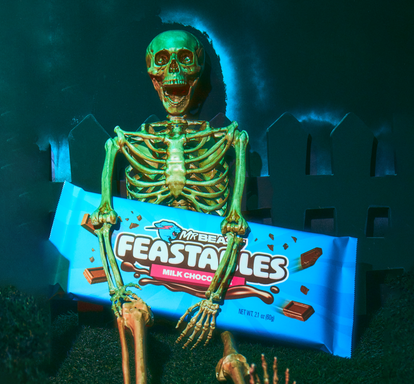 A skeleton holding a giant Feastables chocolate bar